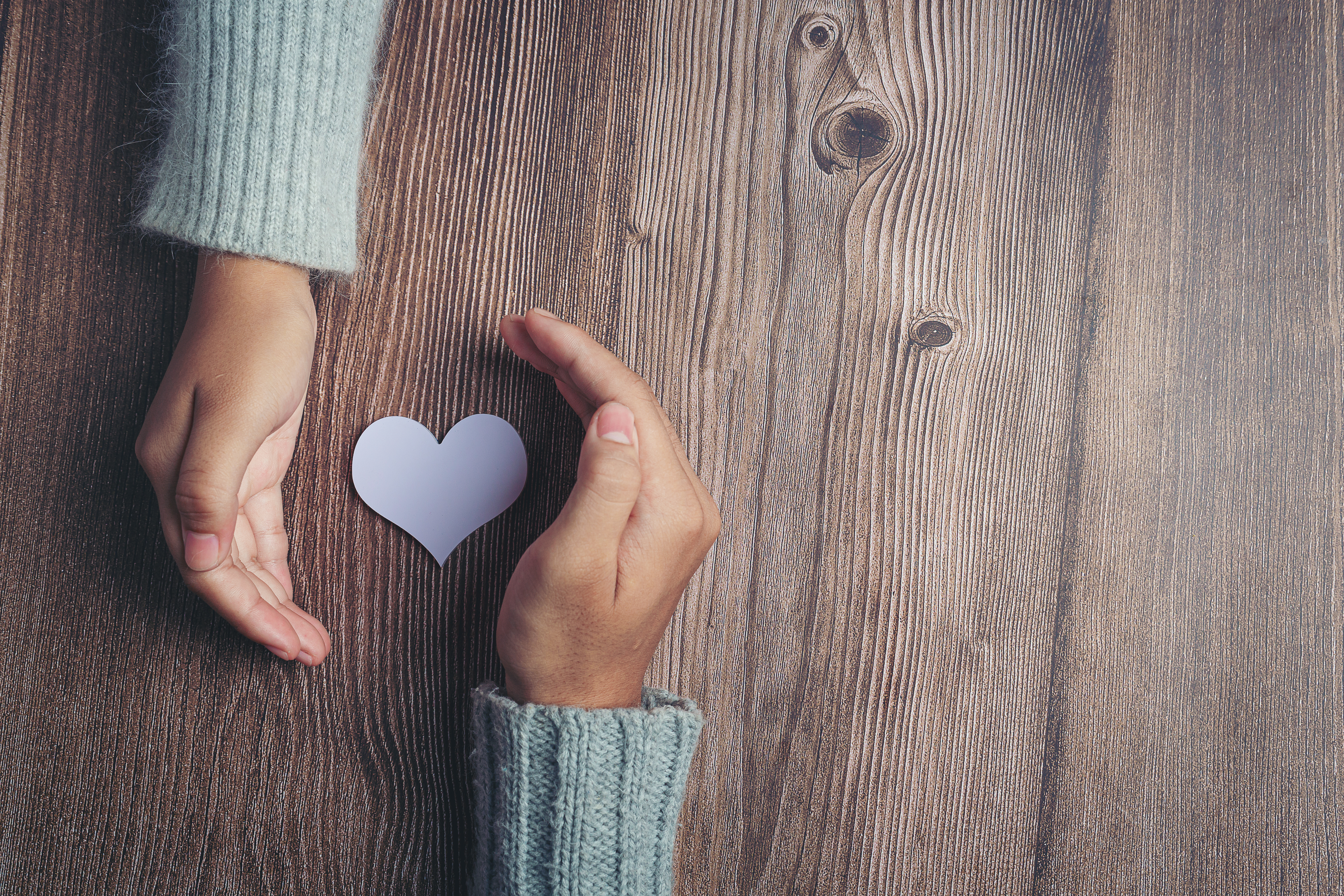 paper-heart-couple-s-hands-wooden-table